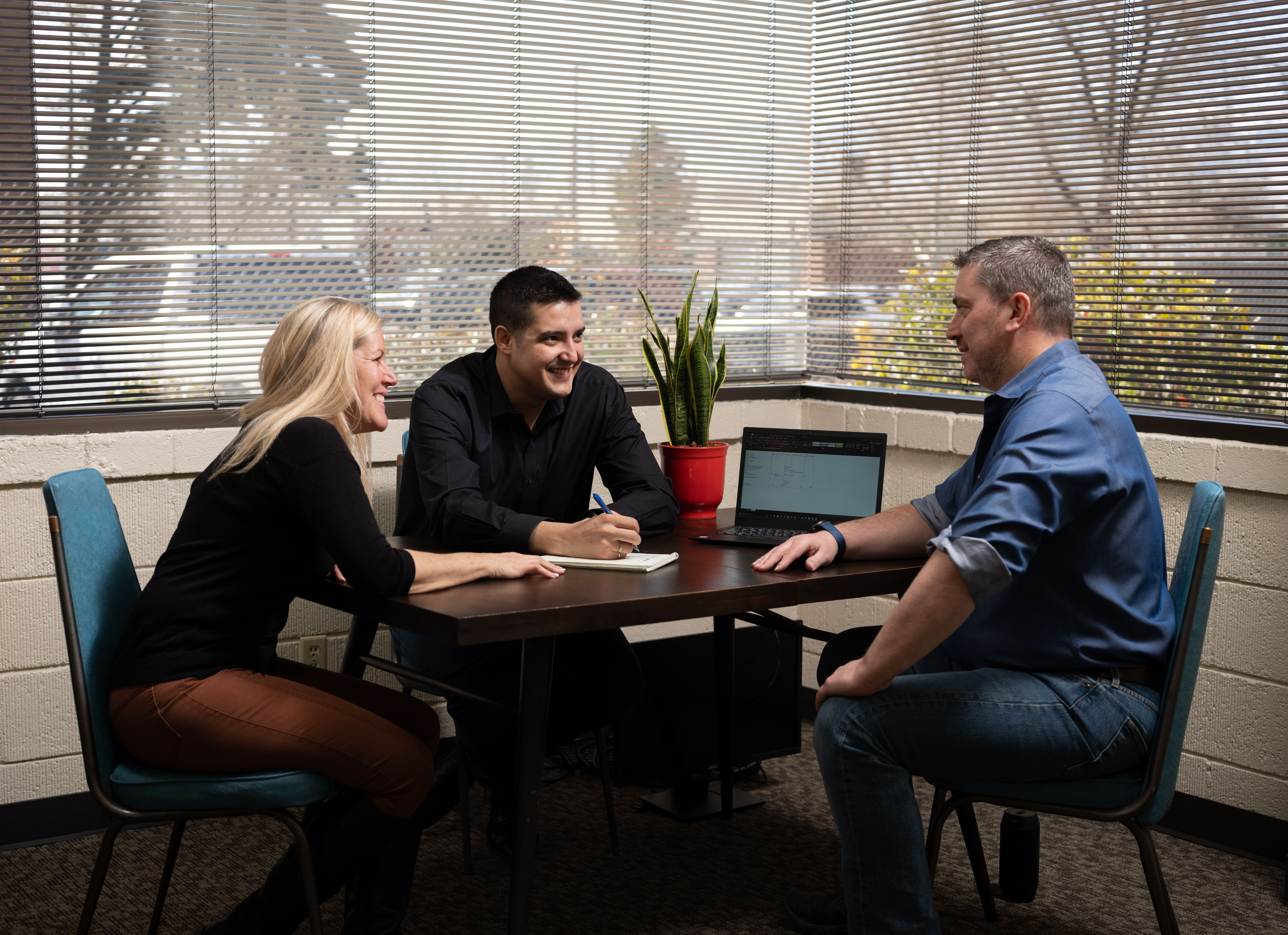 Sierra Miles team members huddle around a computer during a meeting.